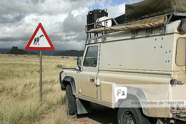 Geländewagen mit Allradantrieb und Giraffen Verkehrsschild in der Savanne  Namibia  Südafrika  Afrika