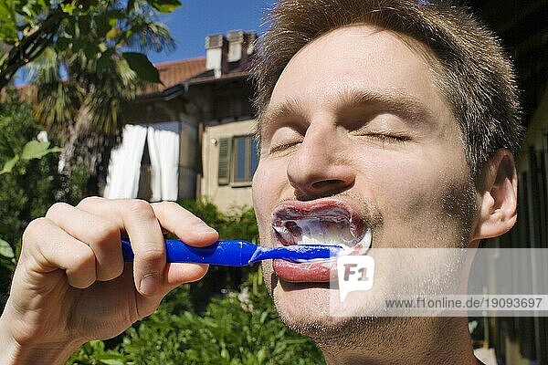 Ein Mann bei der Zahnplege im Freien