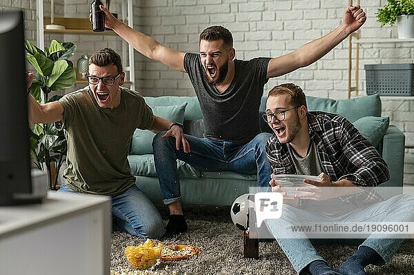 Frontansicht fröhliche männliche Freunde beobachten Sport TV zusammen  während mit Snacks Bier
