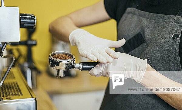 Seitenansicht Barista mit Latexhandschuhen bei der Vorbereitung der Kaffeemaschine
