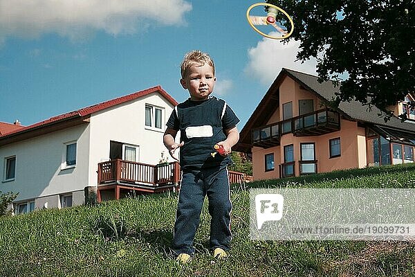 Kleiner Junge spielt mit Propeller-Spielzeug im Sommer