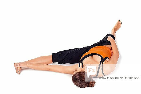 Frau in der Yogapose des liegenden großen Zehs (es gibt vier Versionen dieser Übung)  Sanskrit Name: Supta Padangusthasana  diese Pose dehnt die Hüften  Leisten  Oberschenkel  Kniesehnen  Waden  lindert Rückenschmerzen  Ischias und Menstruationsbeschwerden