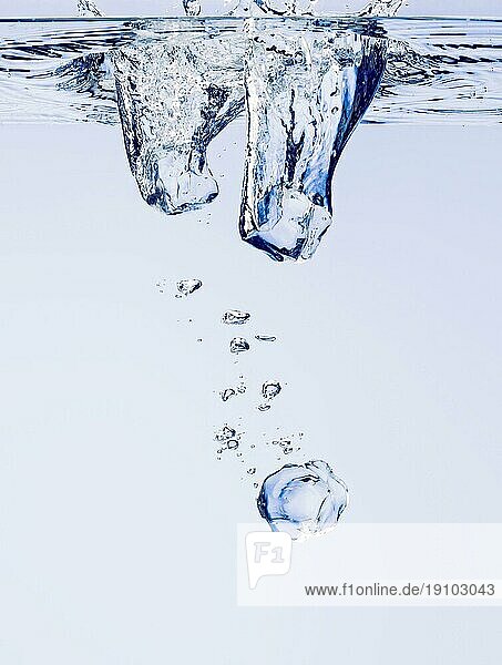 Eiswürfel  die in klares Wasser fallen  mit Blasen