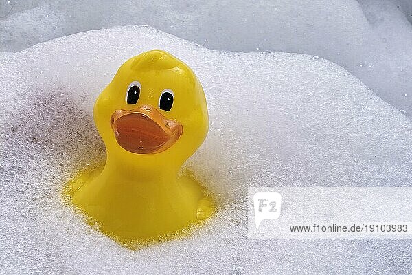 Badeente in der Wanne umgeben von Schaum - Stockfoto