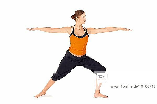 Fit attraktive junge Frau übt Yogaübung genannt Warrior Pose 2  Sanskrit Name: Virabhadrasana 2  diese Haltung stärkt und dehnt Beine  Knöchel  Leisten  Brust  Lunge und Schultern