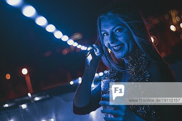 Lächelnde Frau mit champagnerblauen Glaslampen