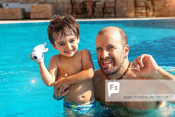 Porträt von Vater und Sohn im Schwimmbad im Sommer spielen genießen und lächelnd im Urlaub