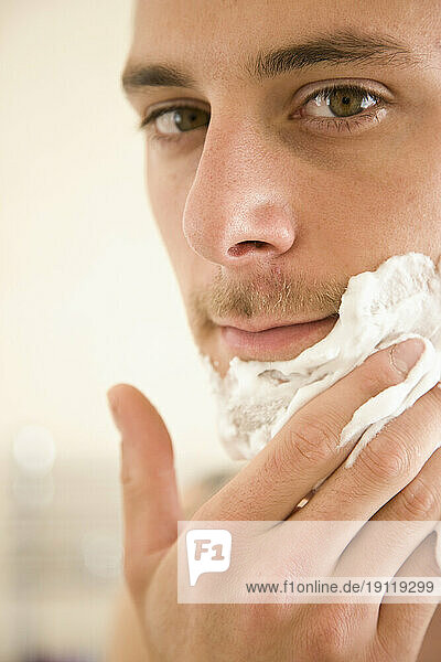 Close up of young man applying shaving cream