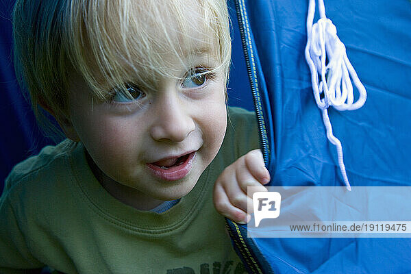 Young blonde boy playing inside a tent