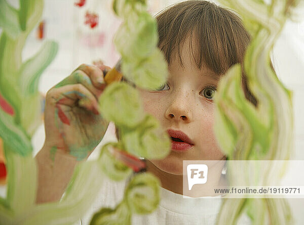 Close up of young girl painting on glass