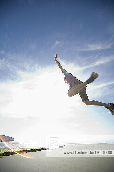 Man in mid air jump on sunny beach