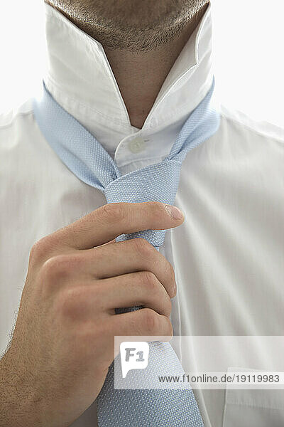 Close up of a young man tightening his tie