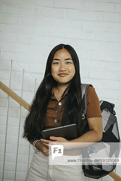Porträt einer lächelnden Studentin mit Rucksack in der Universität
