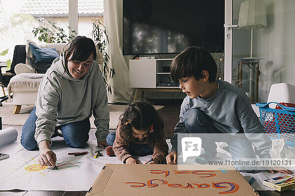 Mutter zeichnet mit Sohn und Tochter im Wohnzimmer zu Hause