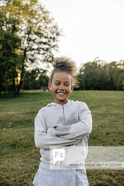 Portrait of smiling girl standing with arms crossed in playground