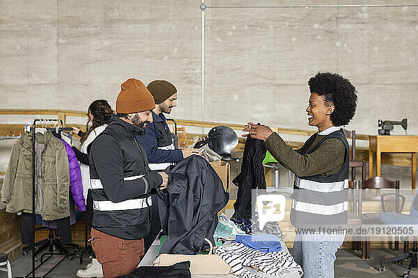 Zufriedene Arbeiter und Arbeiterinnen beim Sortieren von Altkleidern im Recyclingzentrum