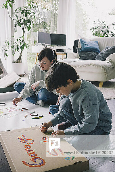 Mutter und Sohn zeichnen im Wohnzimmer zu Hause