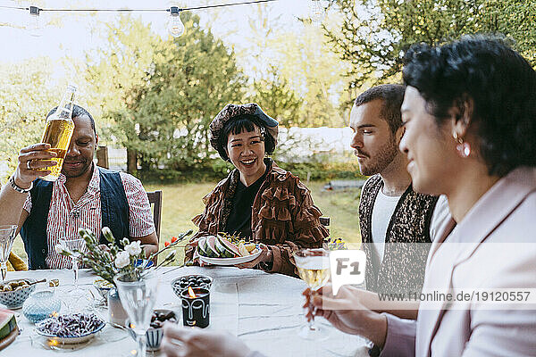 Glückliche Freunde aus der LGBTQ-Gemeinschaft genießen Wein bei einer Dinnerparty im Hinterhof