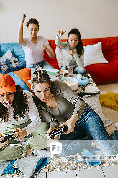 Fröhliche junge Freundinnen spielen ein Videospiel zu Hause