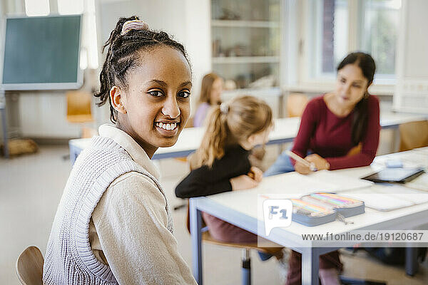 Seitenansicht Porträt einer lächelnden Studentin im Klassenzimmer sitzend