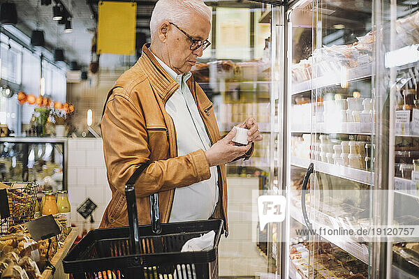 Älterer Mann analysiert Container im Lebensmittelgeschäft