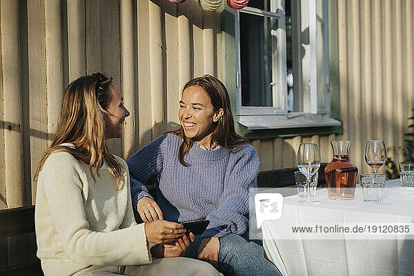 Happy young women talking to each other during dinner party at cafe