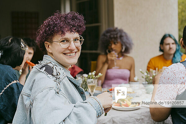 Seitenansicht Porträt der glücklichen nicht-binären Person mit Freunden während der Party im Hinterhof