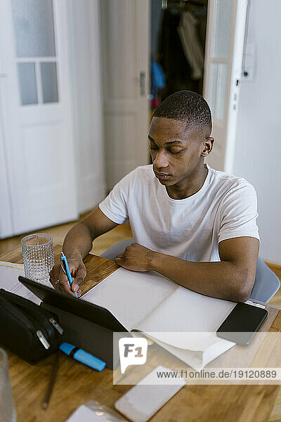 Junger Mann lernt mit digitalem Tablet zu Hause