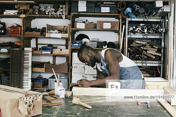 Männlicher Unternehmer beim Upcycling von Holz in der Werkstatt