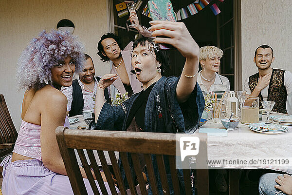Transfrau macht Selfie mit Smartphone mit Freunden aus der LGBTQ-Gemeinschaft während einer Dinnerparty im Hinterhof