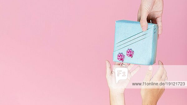 Close up Hand hält eingewickelt Geschenkbox rosa Hintergrund