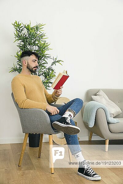 Seitenansicht gut aussehend ernster junger Mann sitzt Stuhl lesen Buch