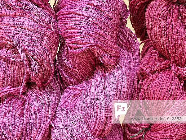 Drei rosafarbene Wollknäuel in unterschiedlichen Farbschattierungen