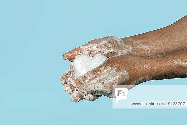 Seitlich stehende Person beim Händewaschen mit weißer Seife