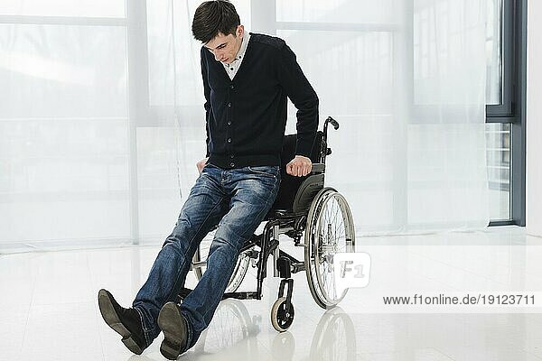 Junger Mann versucht aus dem Rollstuhl zu kommen
