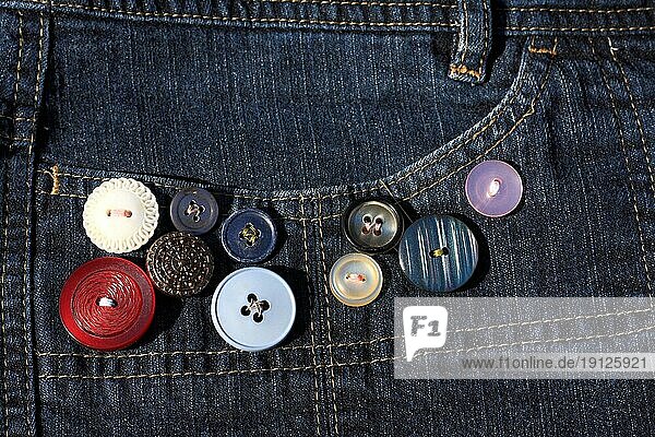 Knöpfe in verschiedenen Farben und unterschiedlichen Grössen  angenäht an der Hosentasche einer Jeans