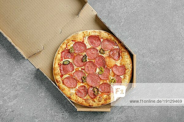 Draufsicht auf pikante Pizza mit Wurst und eingelegter Jalapeno Paprika im Karton
