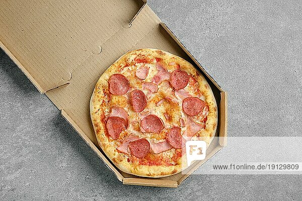 Draufsicht auf Pizza mit Wurst und Schweineschinken im Karton
