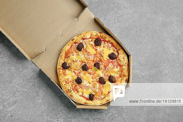 Draufsicht auf eine Pizza mit Rindfleischbällchen  Cheddar und Tomatenscheiben im Karton