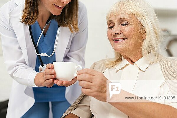 Krankenschwester gibt Tee alte Frau Großaufnahme