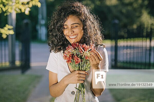 Lächelnde junge Frau hält Blumenstrauß in der Hand
