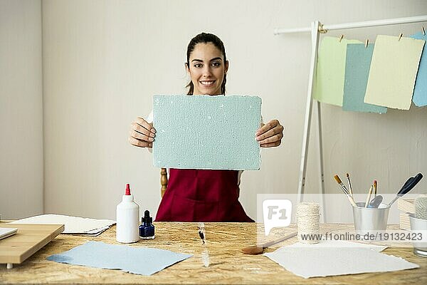 Lächelnde Frau hält handgeschöpftes blaues Papier