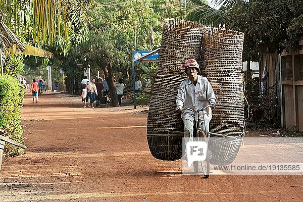 Mann transportiert viele Körbe auf Fahrrad  Dorfstraße  Kambodscha  Südostasien  Asien