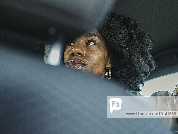 Contemplative woman with curly hair in car