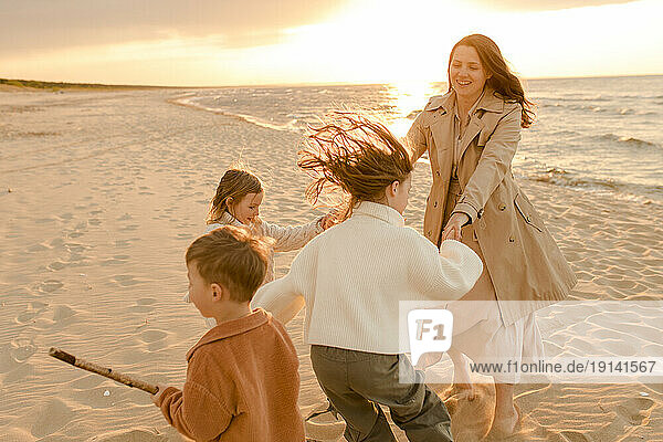 Happy mother having fun with children at sunset