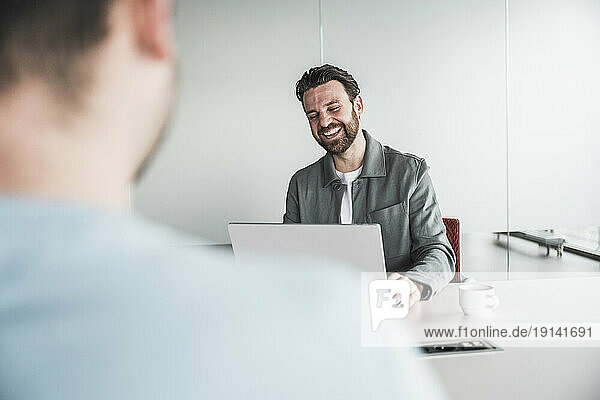 Happy businessman with laptop at office