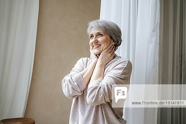 Smiling mature woman day dreaming at home