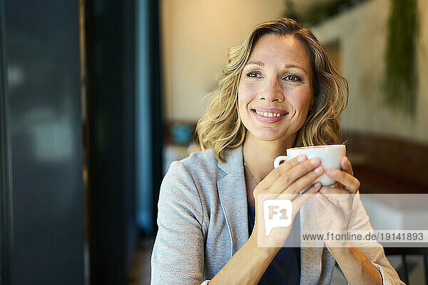 Thoughtful businesswoman day dreaming holding cup at cafe