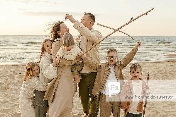Happy family with stick standing and enjoying at beach