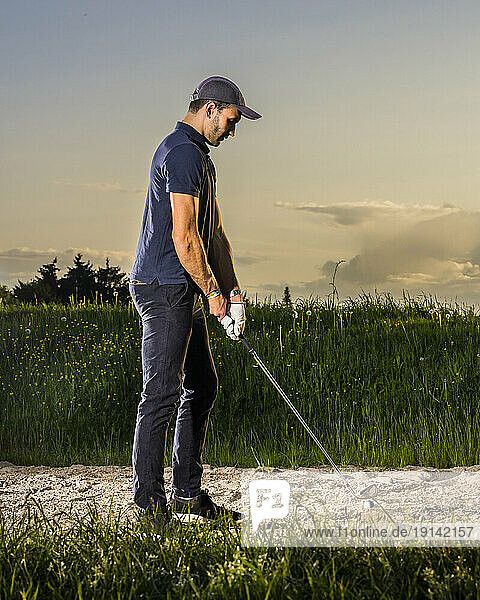 Man preparing to take shot playing golf at dusk